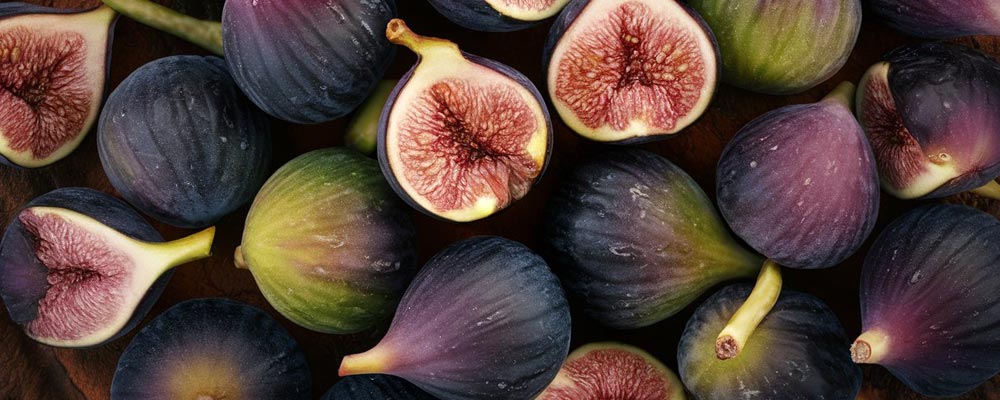 Gros plan sur des figues, dont certaines coupées en deux révèlent leur chair rouge et juteuse. Leur peau violette et leur intérieur texturé mettent en valeur la richesse et la douceur de ces fruits, parfaits pour des collations et des desserts gourmands.