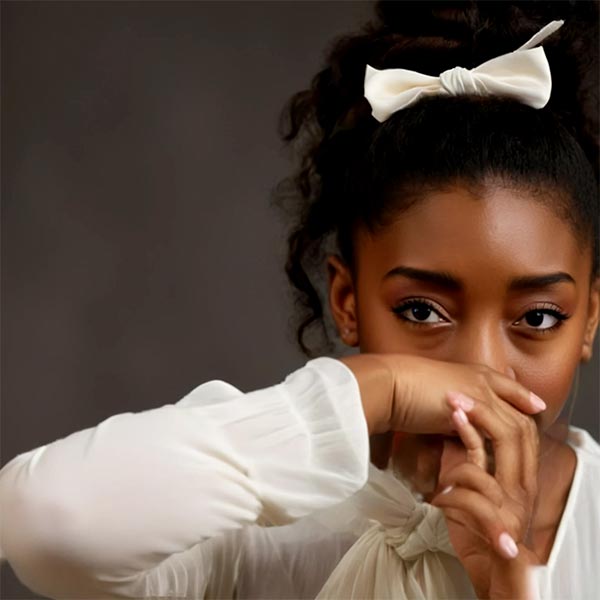 Simone Biles montrant une profonde tristesse avec la main devant son visage. Cette photo illustre le poids émotionnel que porte Simone après avoir révélé publiquement les abus qu'elle a subis.