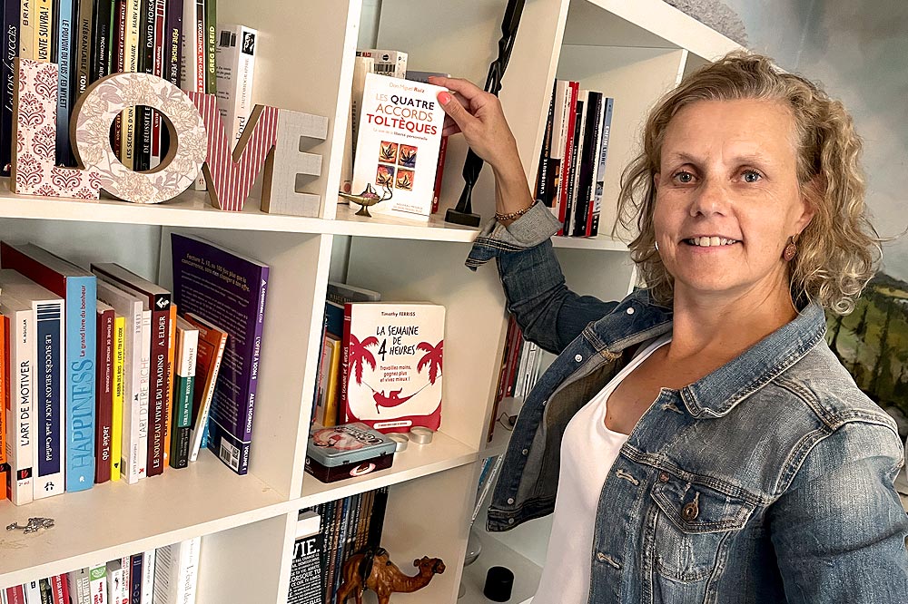 Devant sa bibliothèque, Béa présente les quatre accords toltèques, un des livres sur la confiance en soi qu'elle recommande.