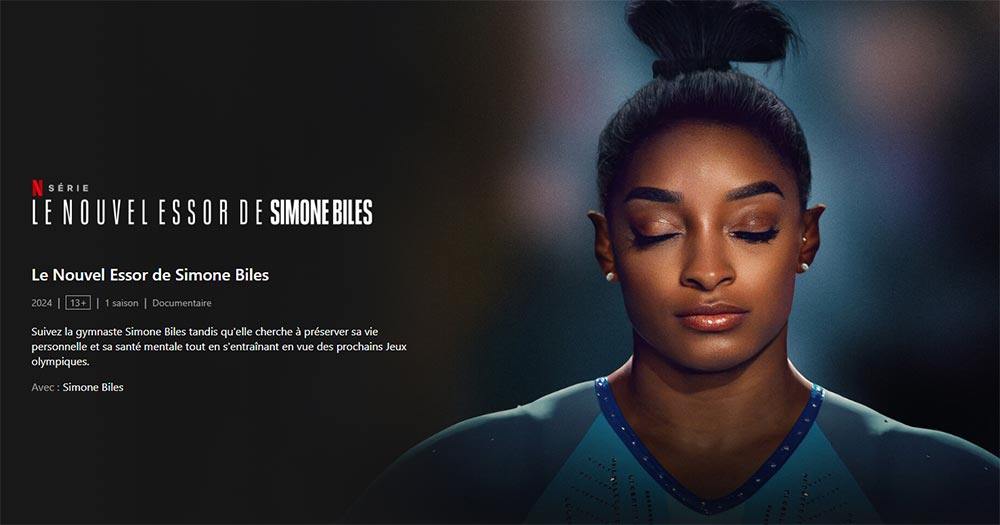 Image de promotion pour la série documentaire Netflix 'Le nouvel essor de Simone Biles', mettant en lumière la gymnaste américaine. On la voit les yeux fermés et concentrée avant de débuter une épreuve de gymnastique.