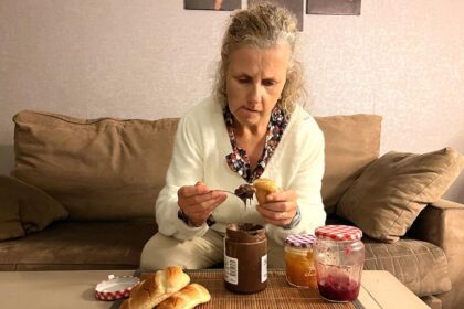 Béa, fondatrice de Femmes en Harmonie, regarde d’un air agacé un pain au lait tartiné de chocolat, symbolisant la difficulté d’arrêter de manger ses émotions face au stress et aux blessures émotionnelles. Te reconnais-tu dans cette habitude de chercher du réconfort dans la nourriture ?