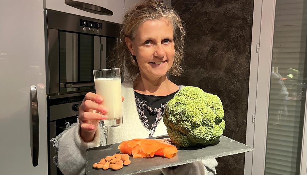 Béa, fondatrice de Femmes en Harmonie, dans sa cuisine présente sur une ardoise différentes sources de calcium essentielles pour des os solides : lait, brocoli, saumon et amandes.