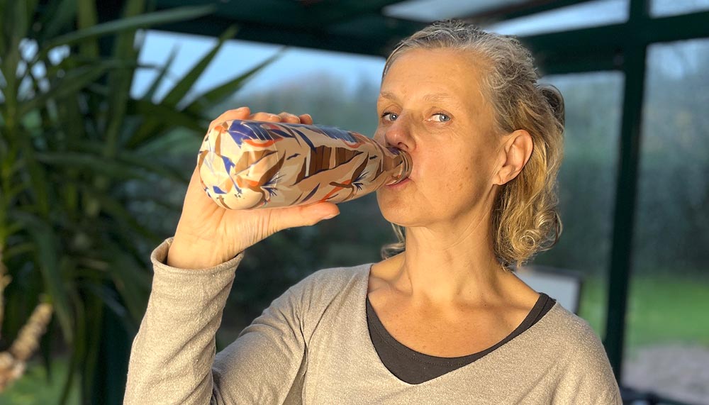 Béa, fondatrice de Femmes en Harmonie, buvant dans une gourde colorée, illustrant l’importance de l’hydratation au quotidien pour maintenir une peau saine, réduire la fatigue et soutenir sa santé. Pourquoi boire de l’eau est essentiel pour un mode de vie équilibré et épanoui.