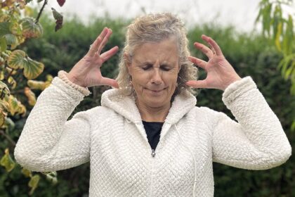 Béa, fondatrice de Femmes en Harmonie, dans son jardin illustrant les premiers signes de la ménopause avec une expression de stress et de tension, et représentant les défis émotionnels et physiques liés à cette étape.