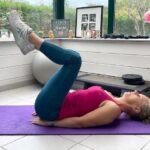 Béa, fondatrice de Femmes en Harmonie, effectuant un exercice de gainage allongée sur un tapis violet, jambes pliées et levées à 90 degrés, pour affiner sa taille, renforcer ses abdominaux profonds et tonifier sa sangle abdominale.