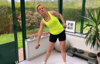 Béa réalise une inclinaison latérale avec haltères pour travailler les obliques et la sangle abdominale. Cet exercice fait partie des exercices pour brûler les graisses ciblés sur la taille, permettant de sculpter la silhouette, renforcer le centre du corps et favoriser une combustion douce mais efficace des graisses, sans impact articulaire.